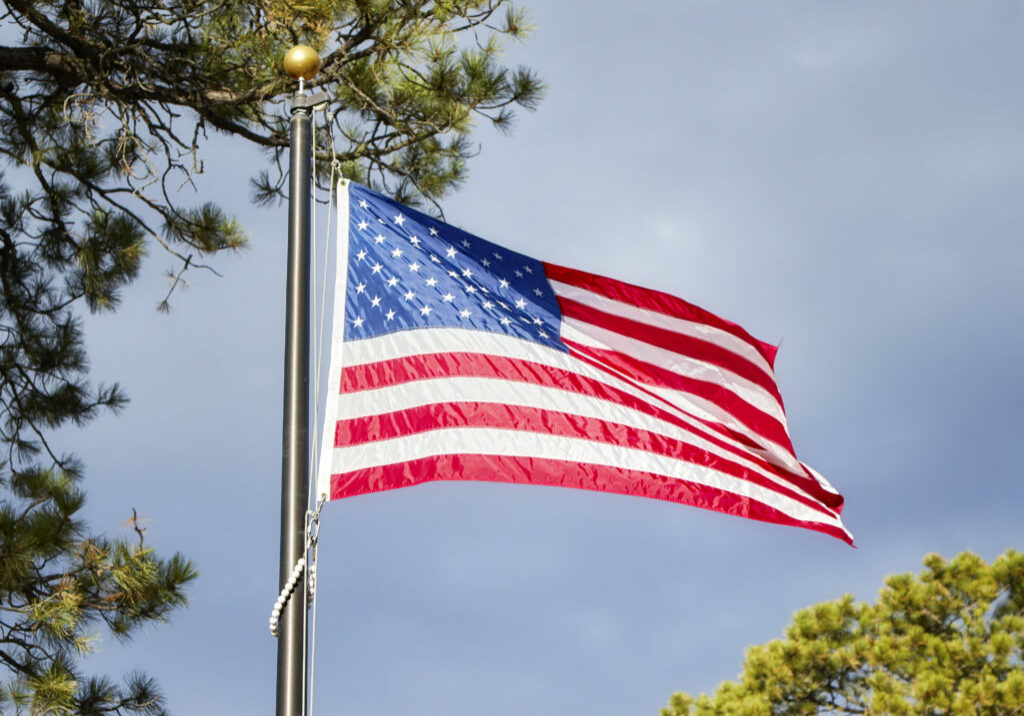 American flag blowing in the wind in a park, selective focus.