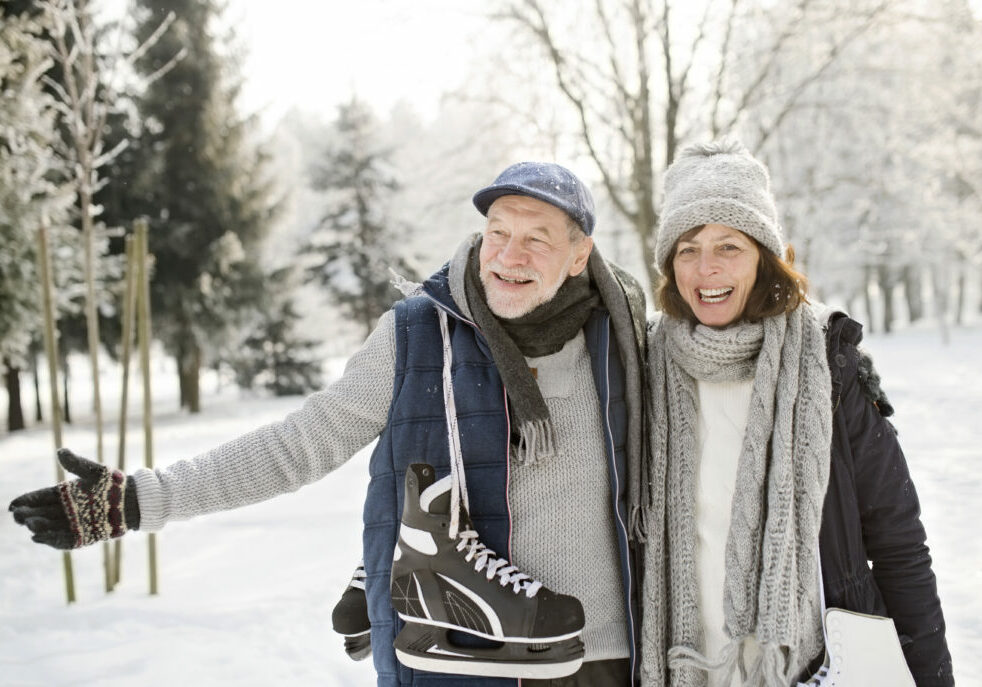 Happy senior couple with ice skates in winter landscape
