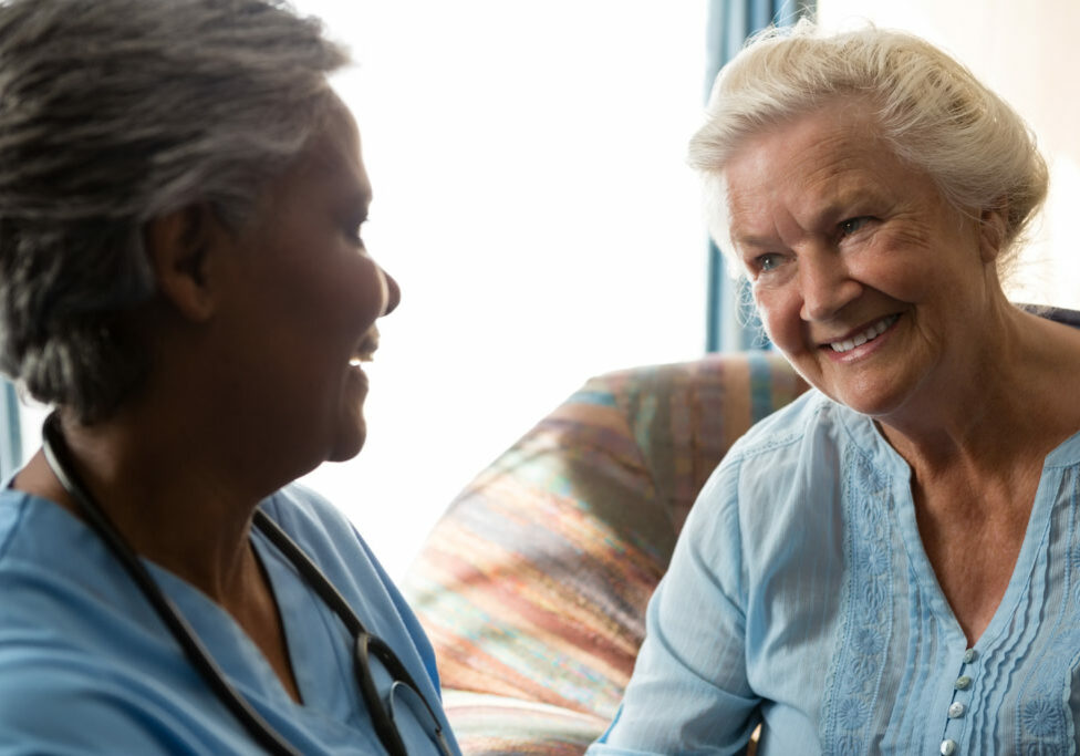 Smiling nurse talking to senior patient in nursing home